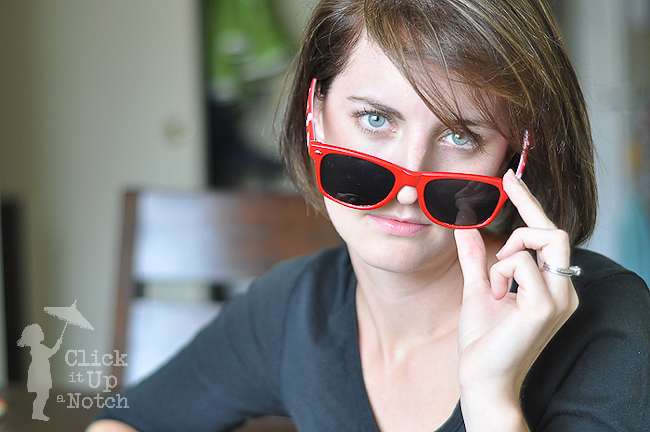 Photo of woman wearing red sunglasses with catchlights in both eyes.