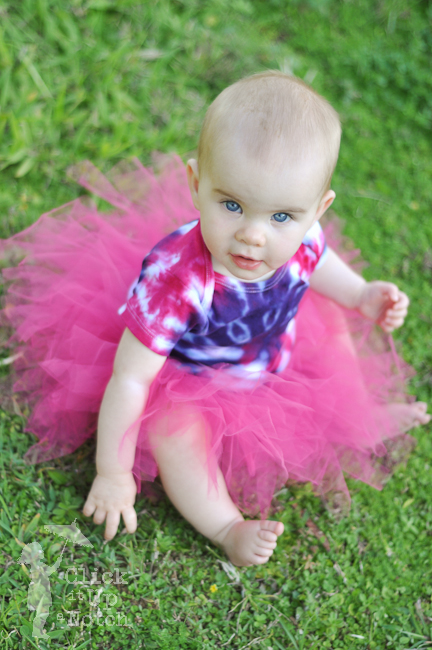 Child in pink tutu looking up at the camera so there are catchlights in her eyes. 